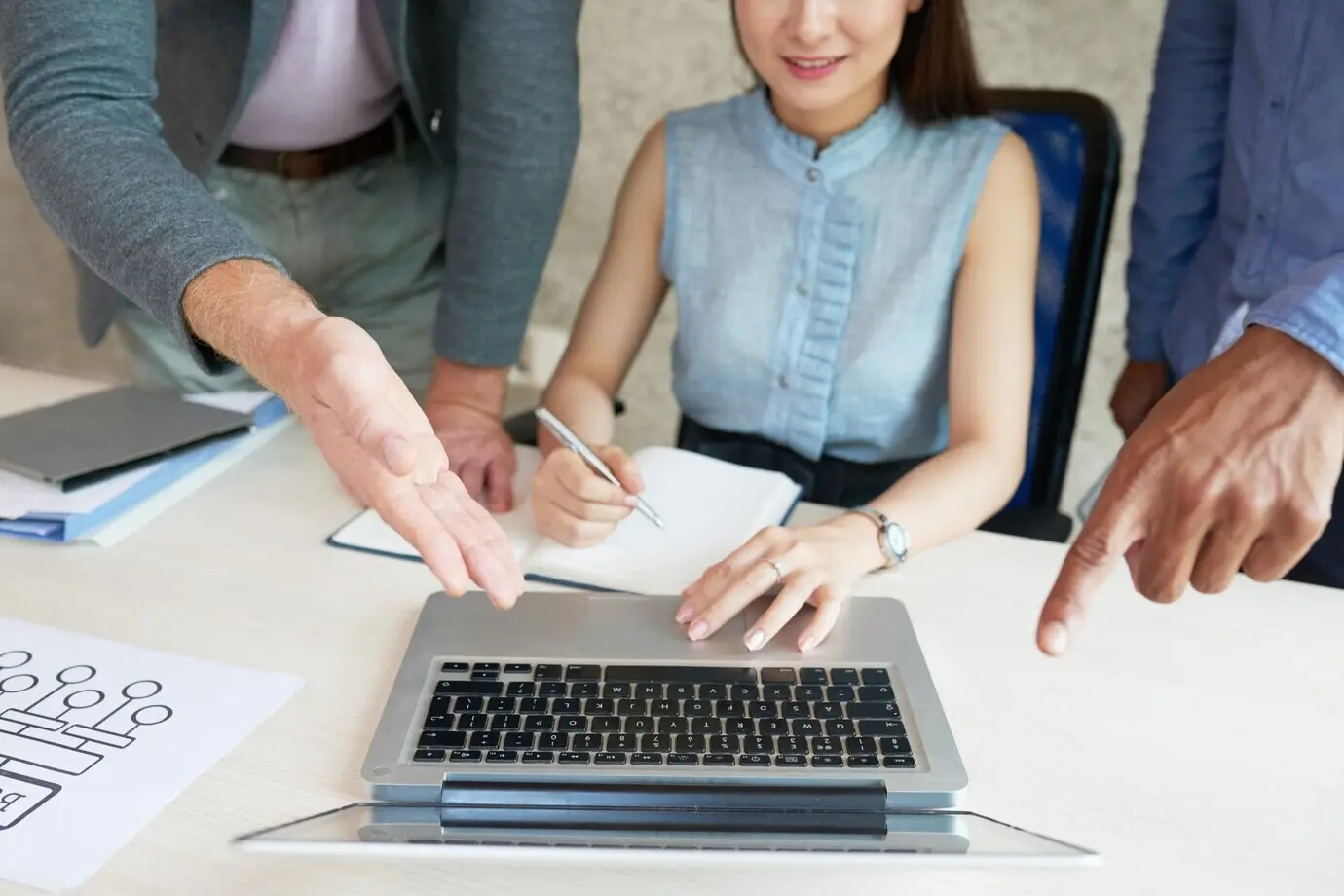 Colegas irreconocibles mirando y señalando la pantalla de un portátil en una reunión de trabajo.