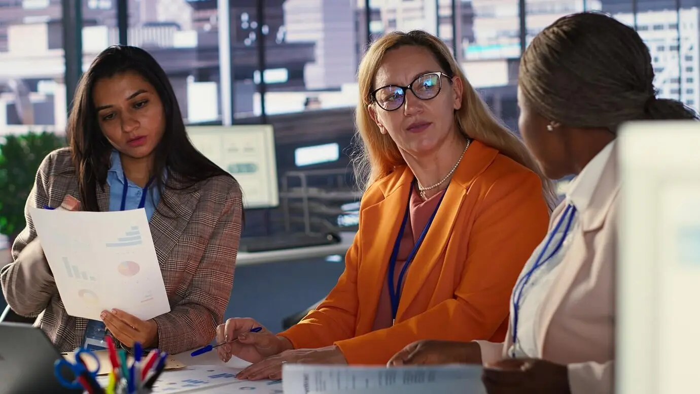 Mujeres ejecutivas ambiciosas que colaboran en un entorno laboral diverso.